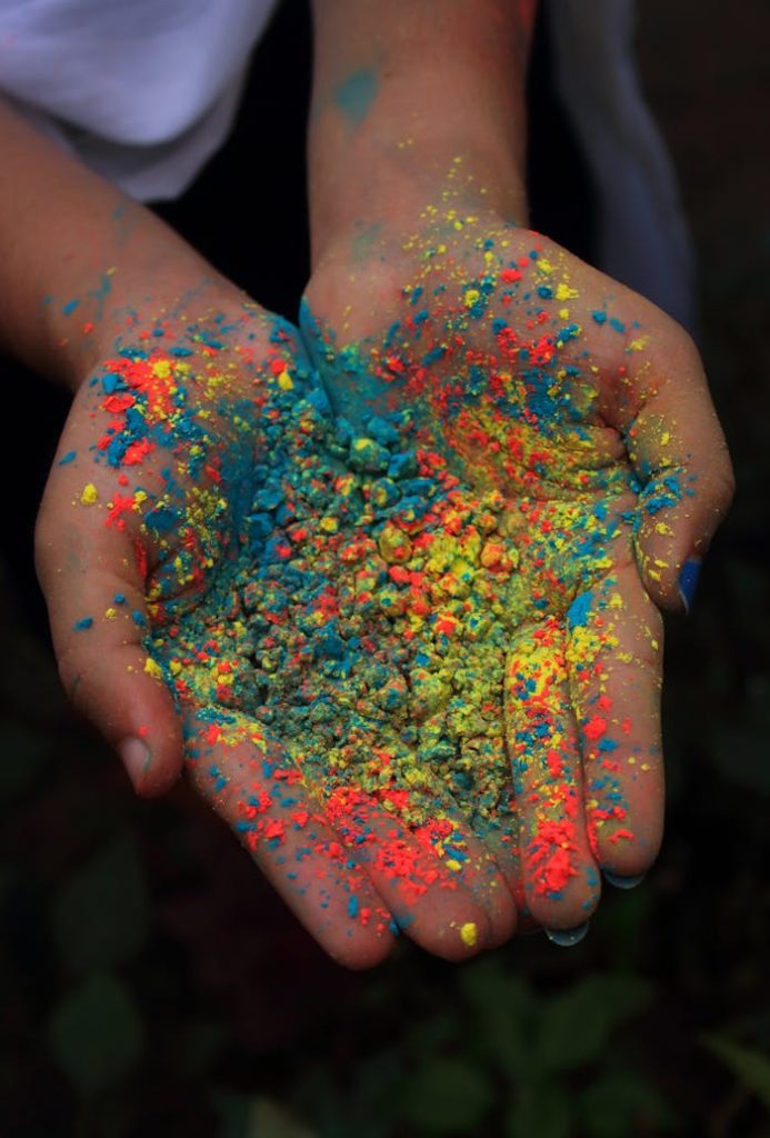 Hands holding vibrant Holi powder, symbolizing joy and celebration in India.